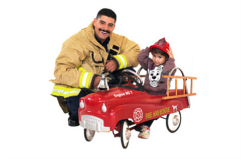 Firefighter with Boy in Toy Fire Engine
